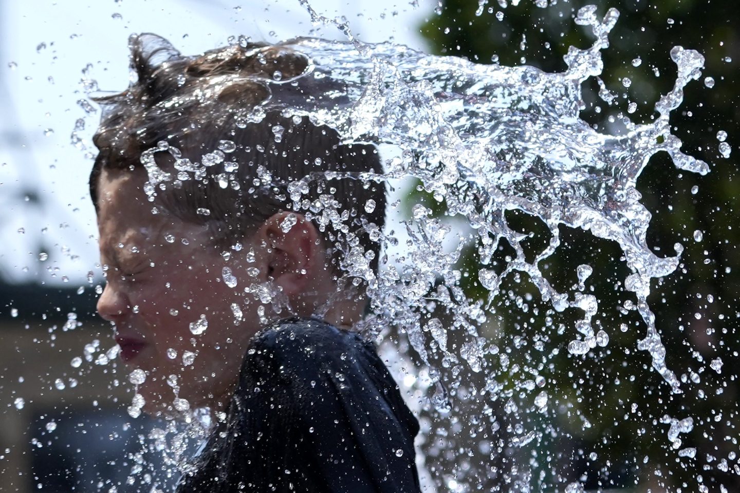 A boy cools off at a fountain during hot weather in Chicago, on June 16, 2024.