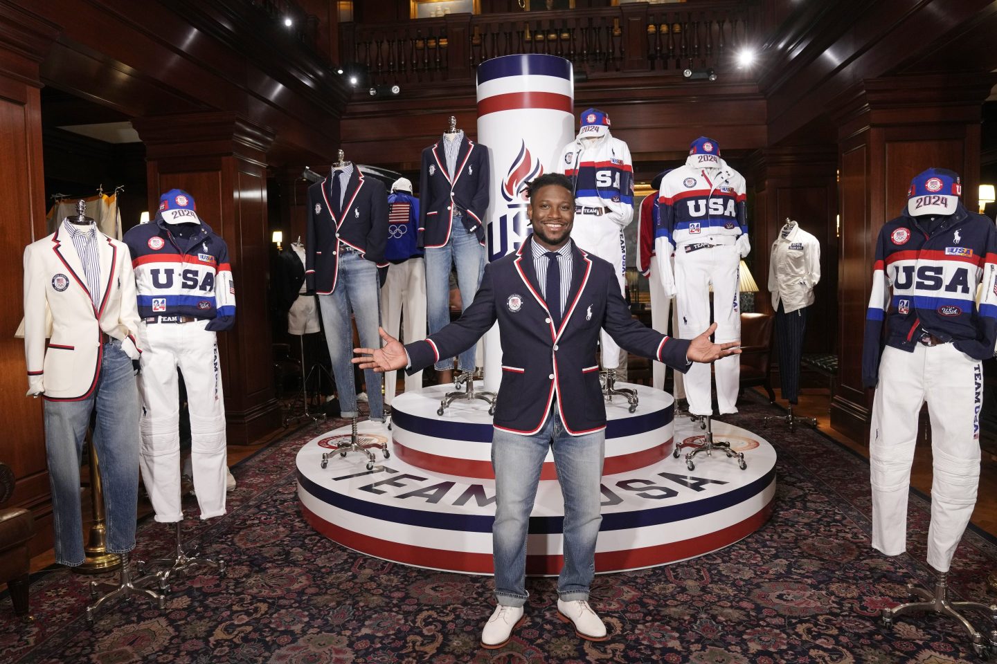 U.S. Fencer Daryl Homer, wearing a suit jacket and jeans, poses in front of a Ralph Lauren display.