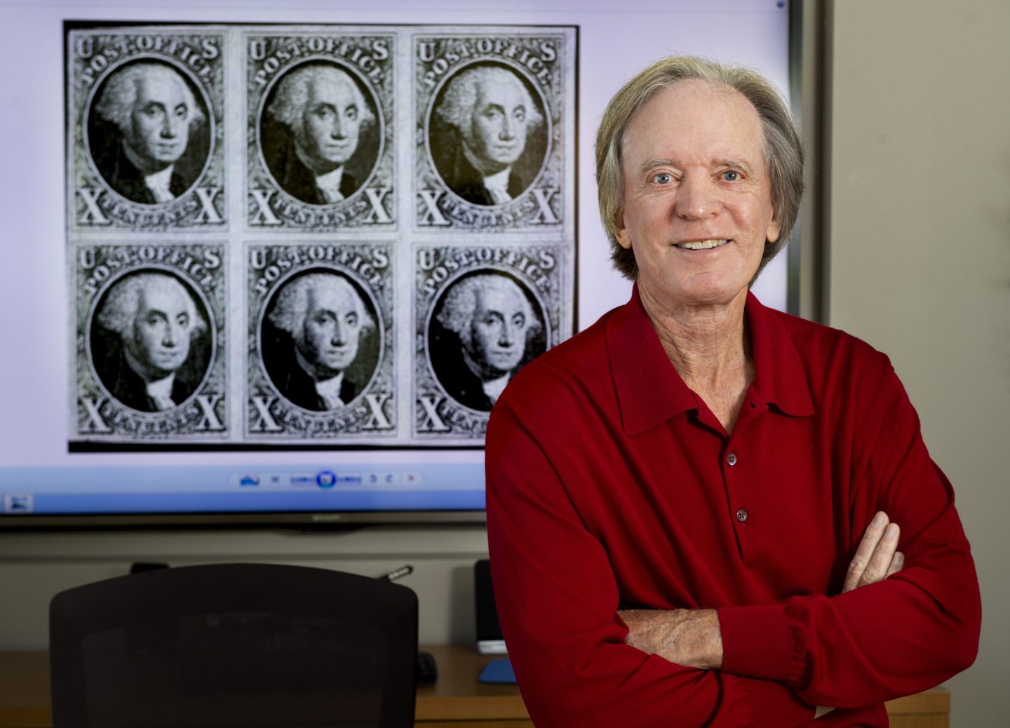 Bill Gross sit in front of image of old stamps