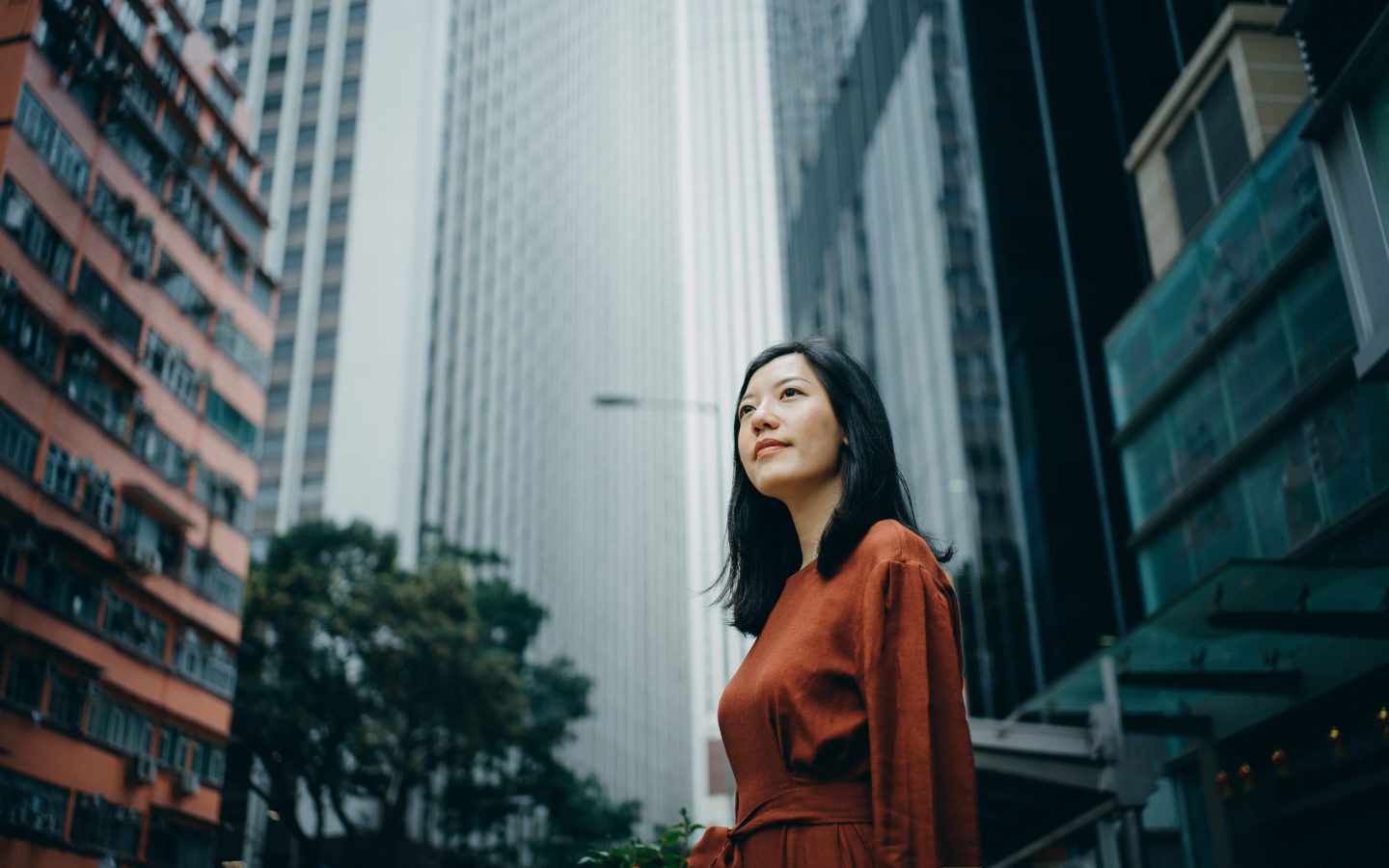 Low angle portrait of confidence young woman standing against highrise city buildings in city