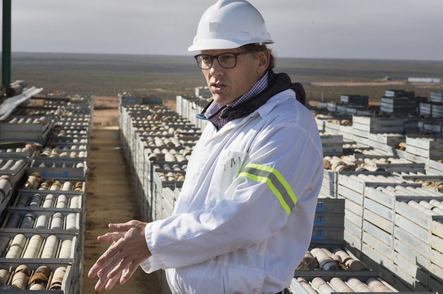 A man in a hard hat stands outside of a rare earth mineral mine.