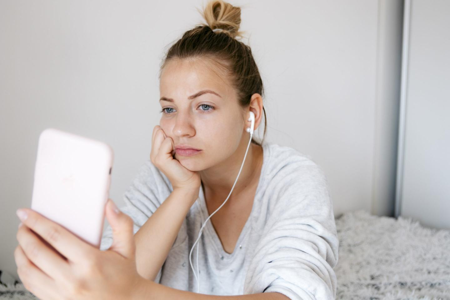 Young woman looks sad as she holds a smartphone