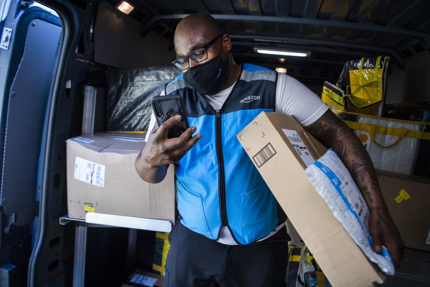 Amazon driver in blue vest looks at phone