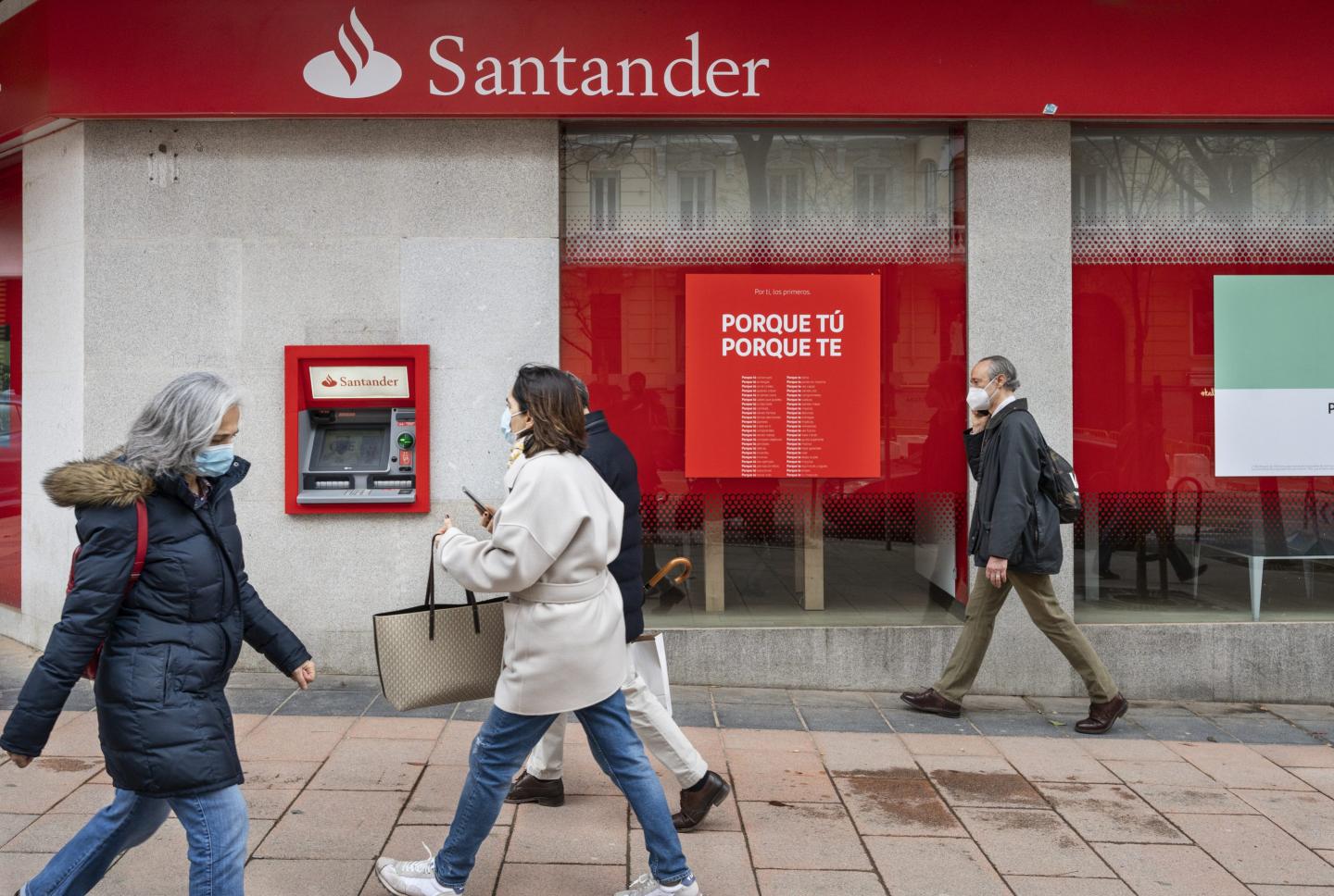 Pedestrians walk past Santander branch in Spain.