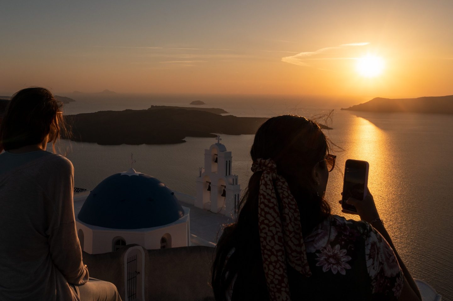 Tourists taking pictures and watching the sunset in Santorini, Greece.