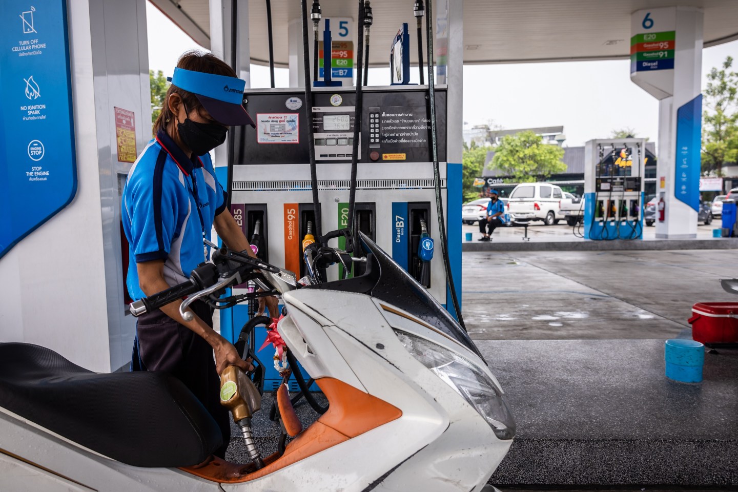 An employee refuels a customer's motorcycle at a PTT gas station in Bangkok, Thailand.