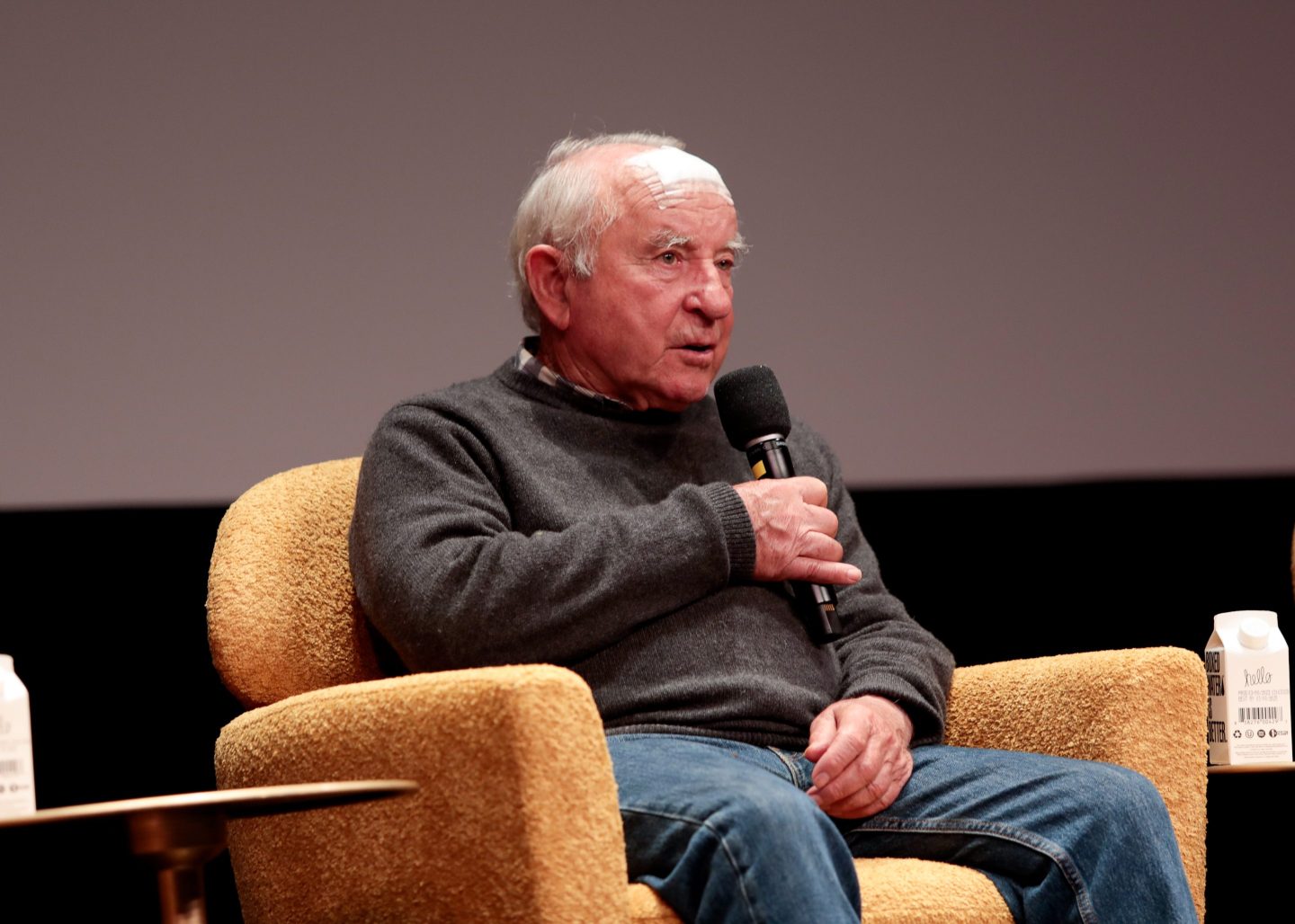 Yvon Chouinard, Patagonia's founder, sits in a chair holding a microphone.