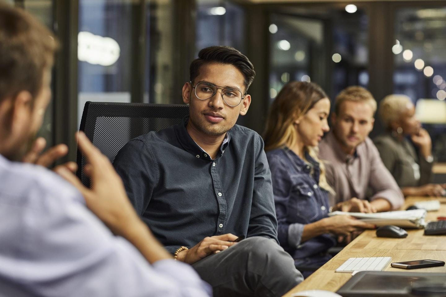 Businessman explaining colleague while sitting at desk. Male and female professionals are working in creative office. They are wearing smart casuals.