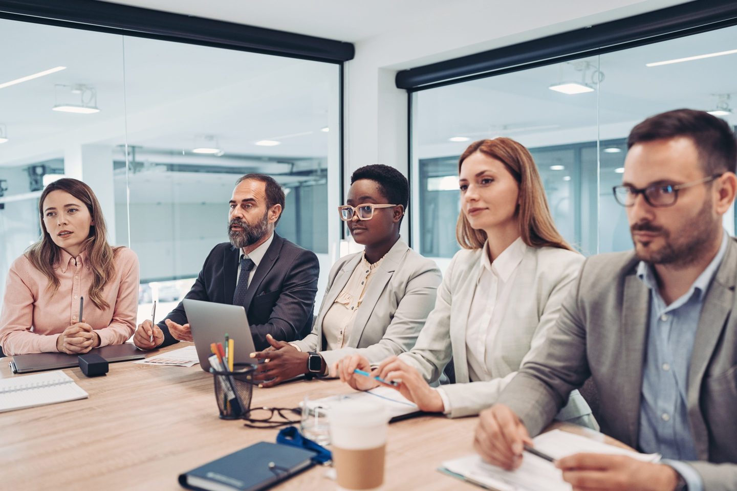 A group of business leaders sit in a meeting.