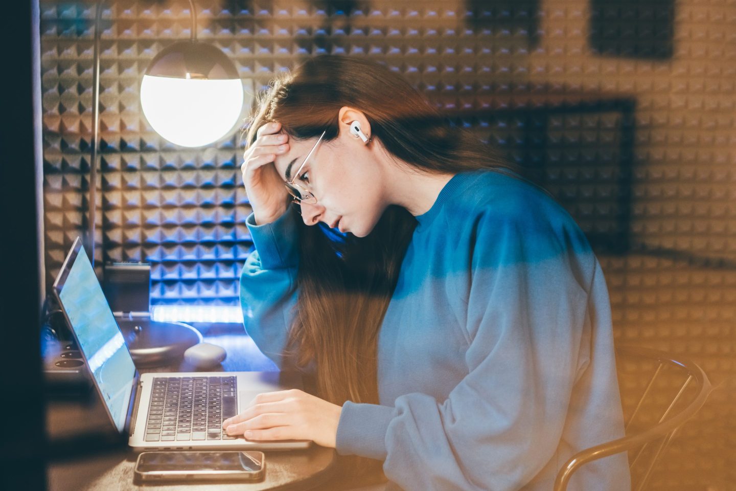 A woman sits at her computer with her head in her hand, looking frustrated.