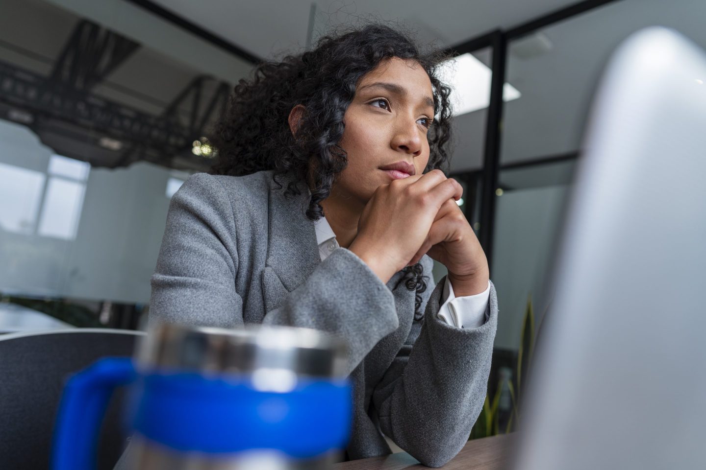 A woman leaning on her desk on her elbows and looking distressed