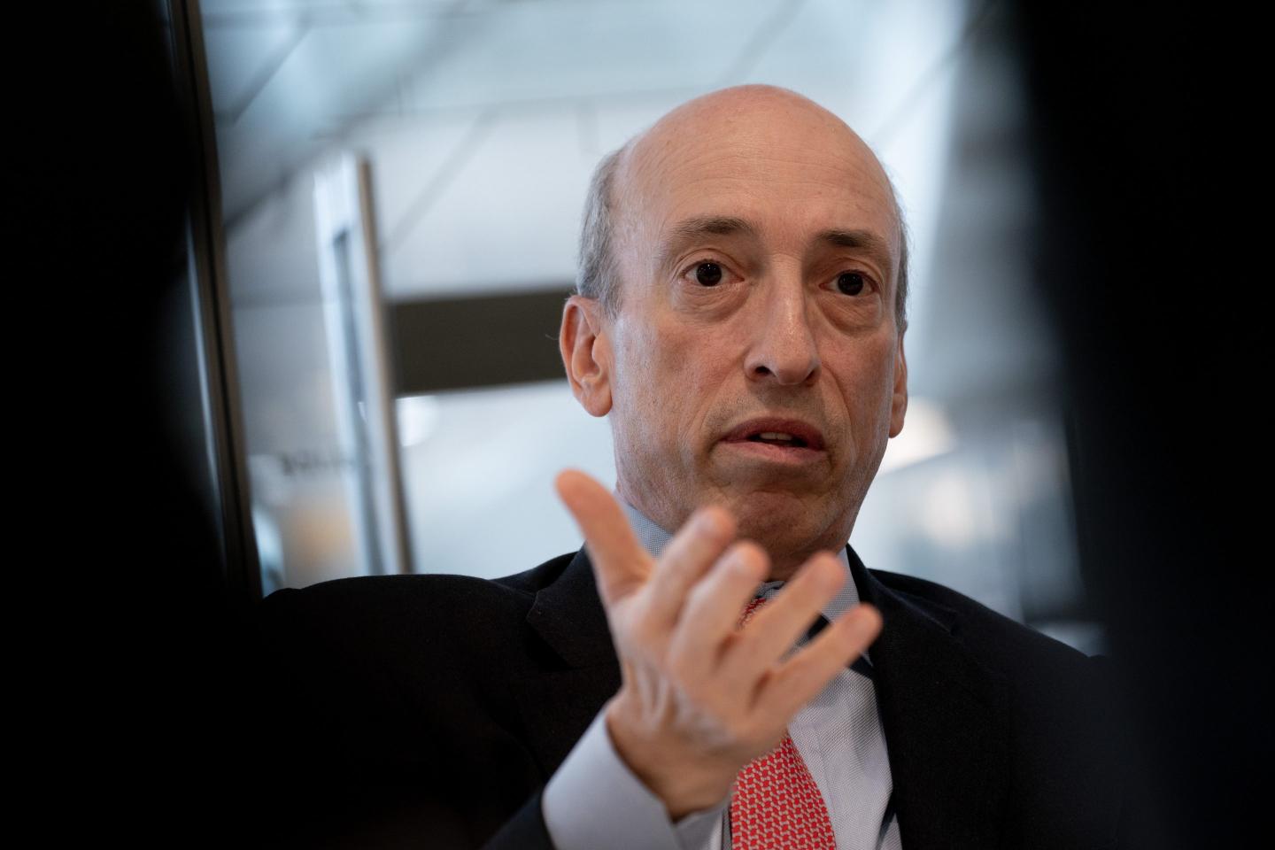 Gary Gensler, wearing a suit, has his hand in front of him as he gestures and frowns.