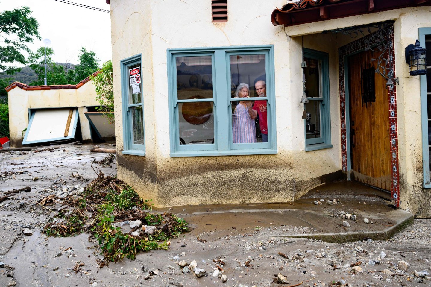 Residents trapped in their home peer out a window while waiting for help in Yucaipa, California in the aftermath of Storm Hilary in August 2023.