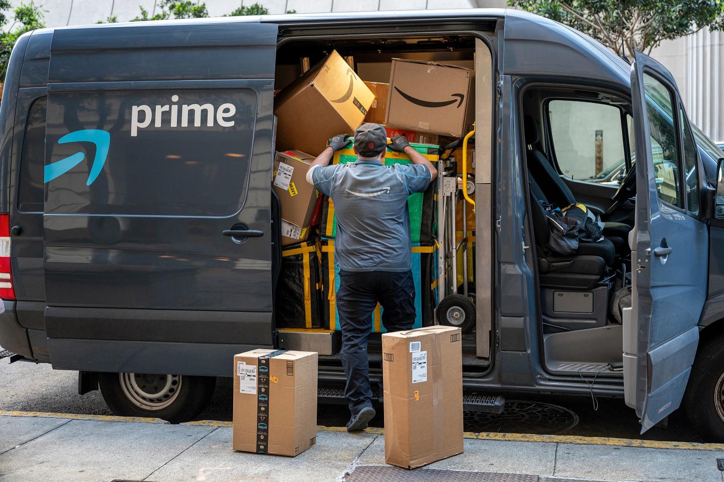 An Amazon delivery driver unloads boxes from a crammed van.