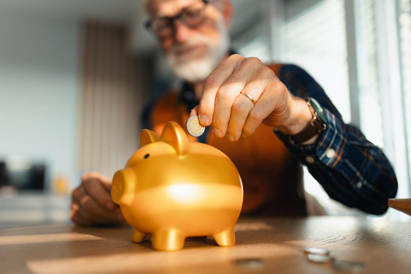 Male worker puts money in piggybank.