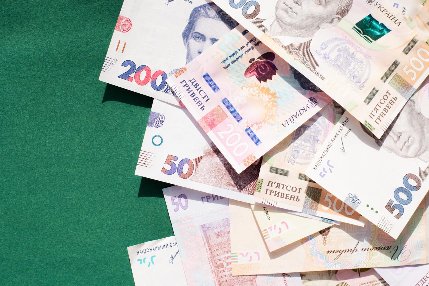 Several Hryvnia banknotes, the currency of Ukraine, sit on a table.