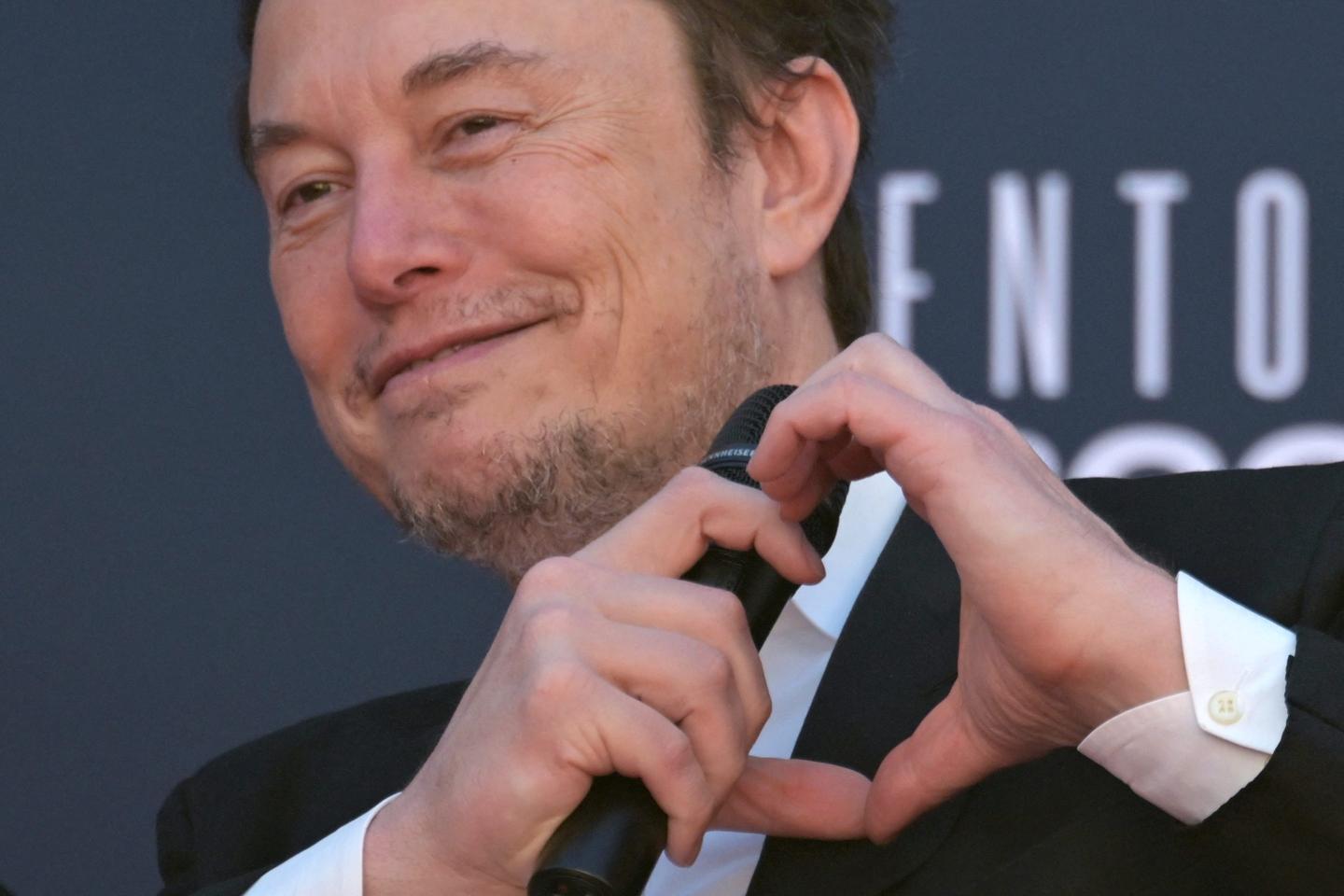 Elon Musk forms a heart sign with hands