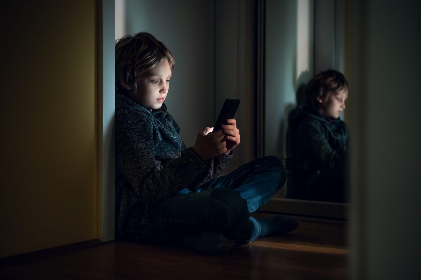 young boy sitting in the dark on his smartphone