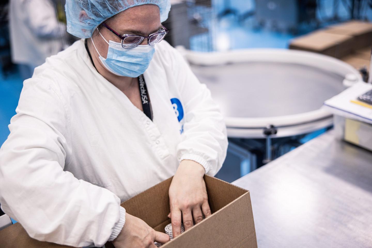 A factory worker packs supplements inside a box.