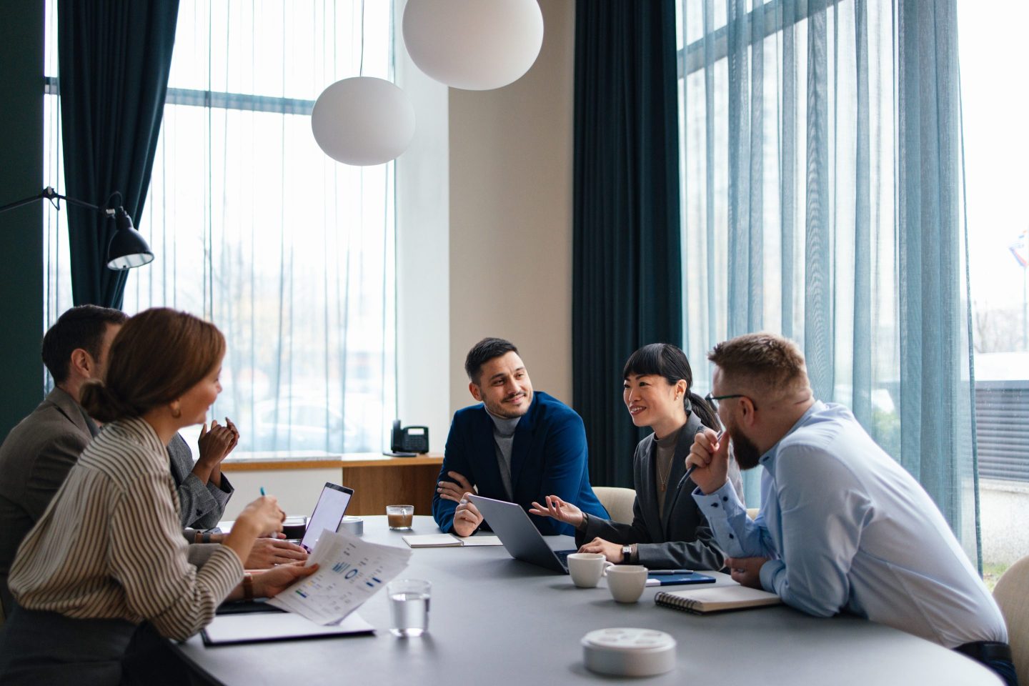 Close up shot of a beautiful smiling businesswoman, sitting at her desk at the office, looking down and using her laptop computer.
