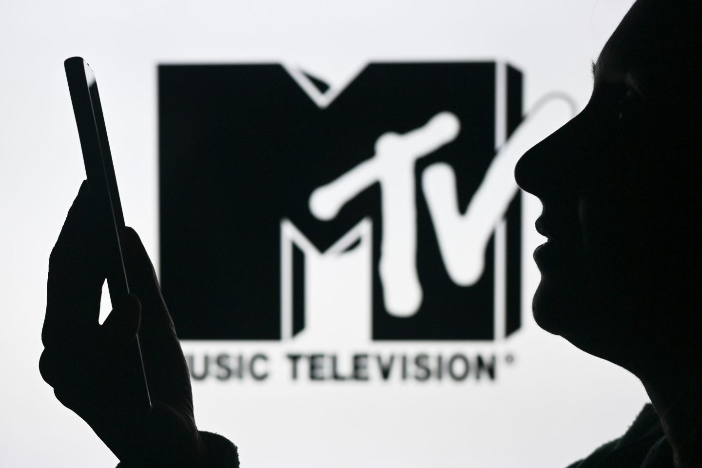 An image of a woman holding a cell phone in front of the MTV logo displayed on a computer screen, on April 29, 2024, in Edmonton, Canada.