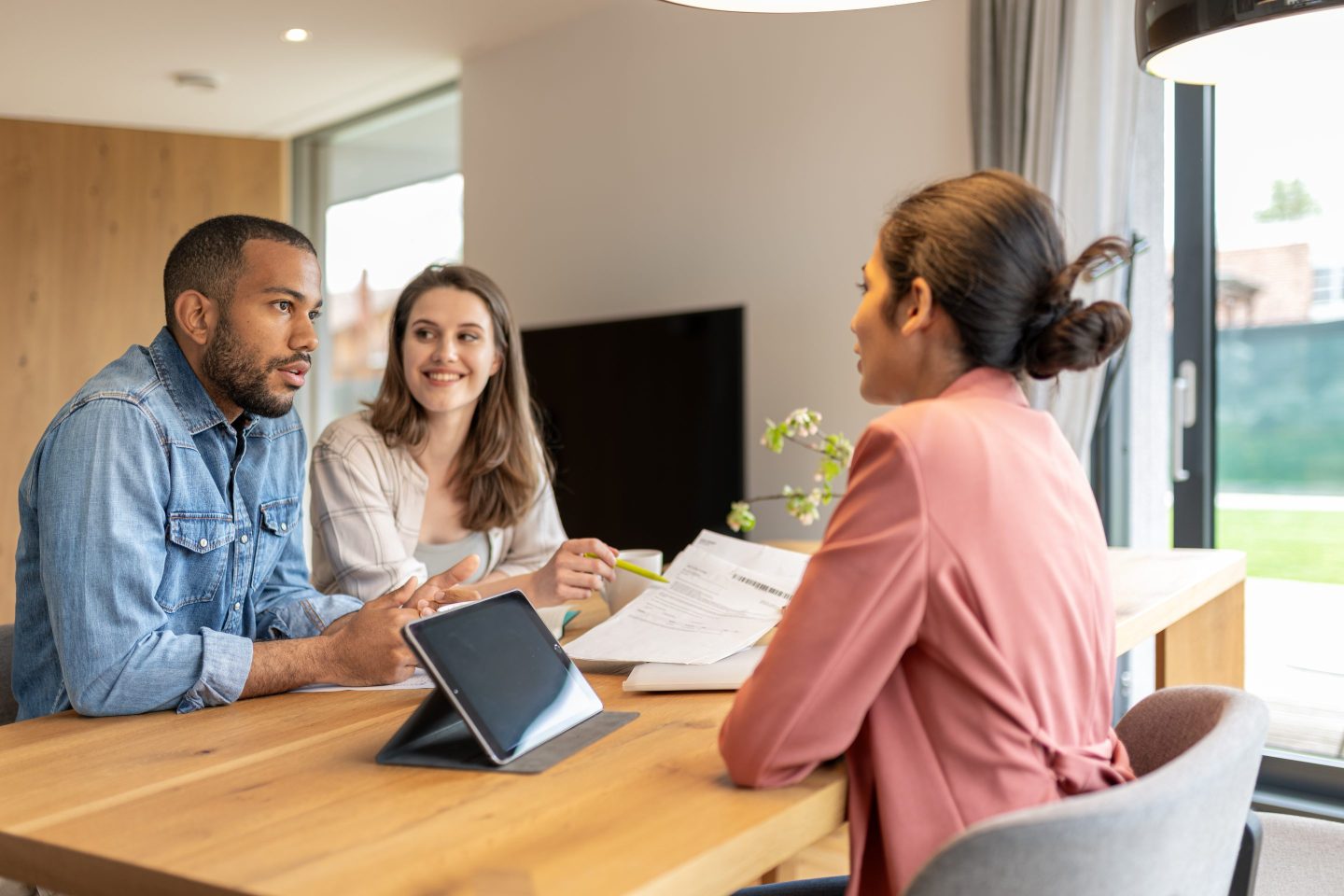A financial advisor advises a multiracial couple at home