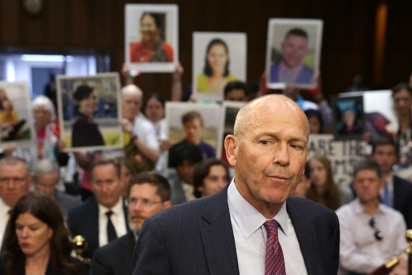 Relatives of Boeing airplane crash victims demonstrate before Boeing President and CEO Dave Calhoun (front) testifies before a Senate subcommittee hearing to examine "Boeing's broken safety culture" on Capitol Hill in Washington, DC, June 18, 2024.
