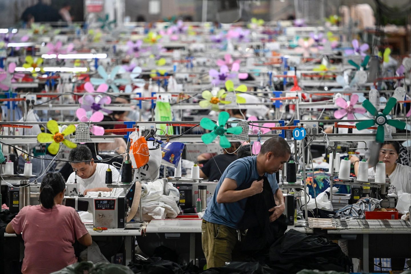 Several workers at sewing machines, producing garments at a textile factory in China