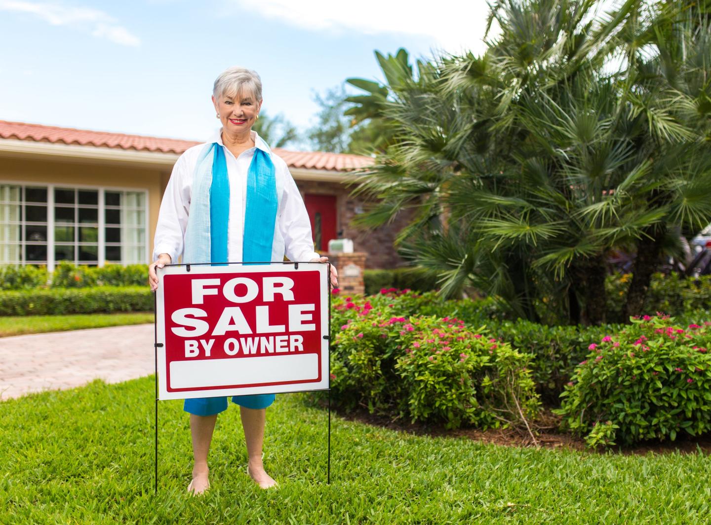 Real Estate agent putting a For sale sign in a yard.