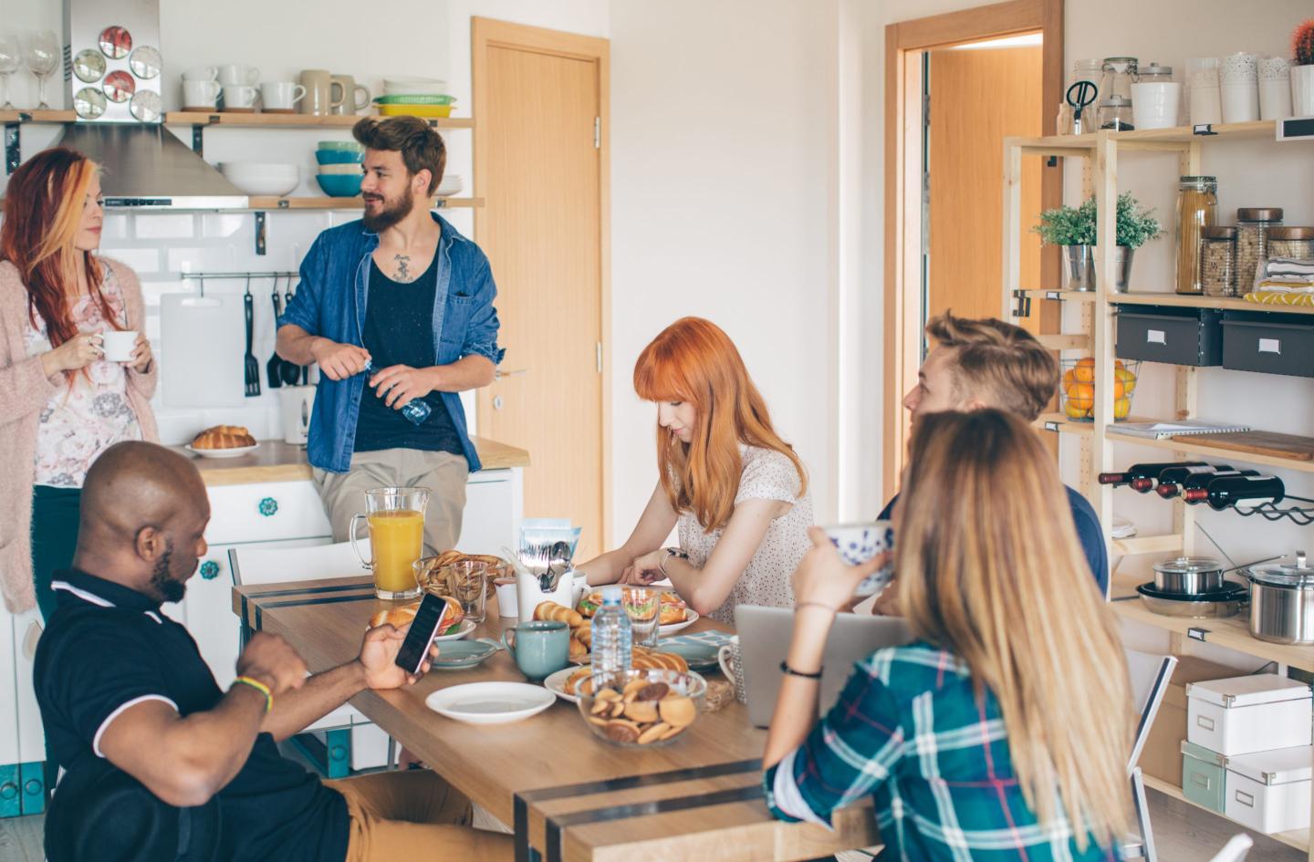 Group of young people having breakfast at a common kitchen