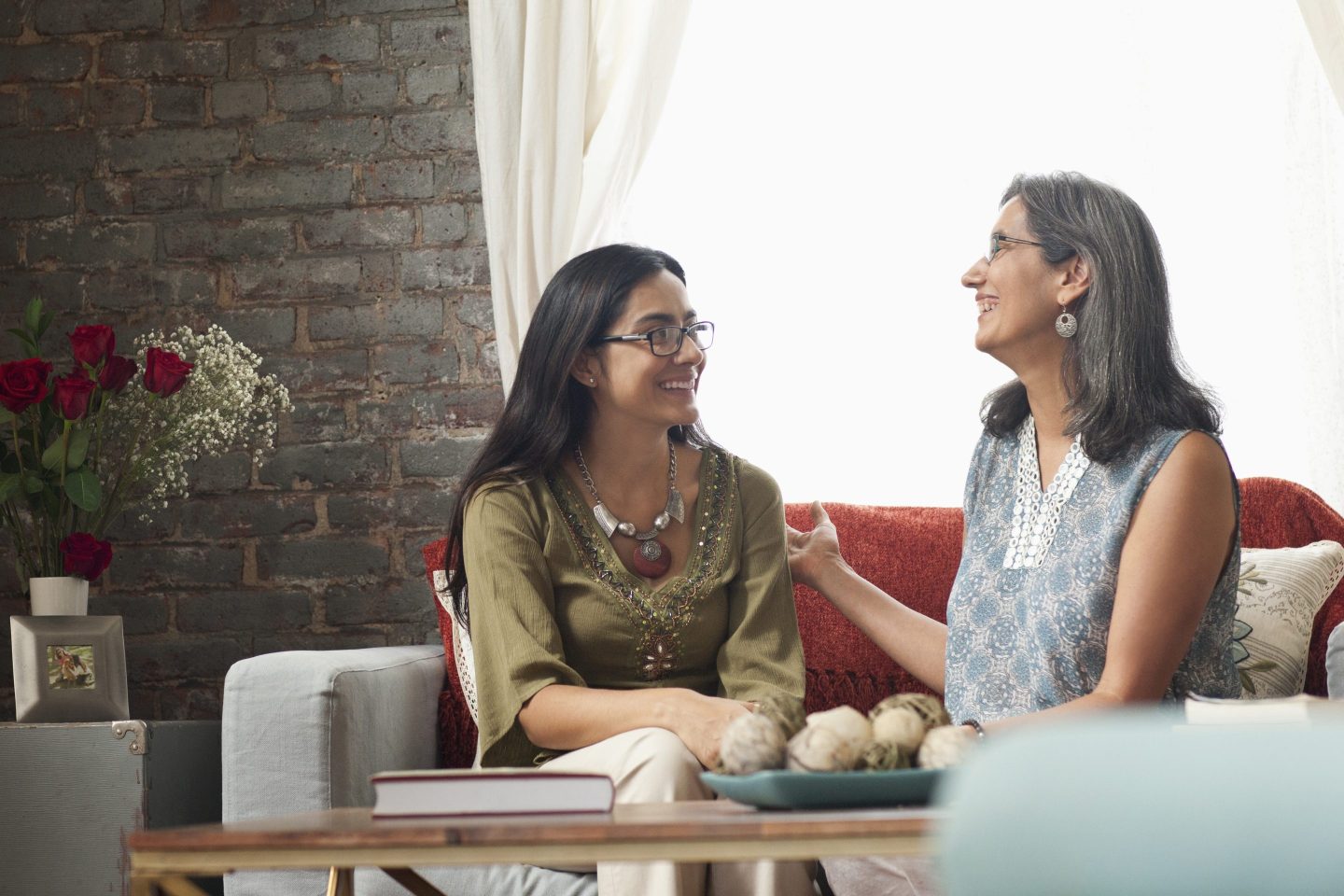 Happy mother and daughter laughing on sofa