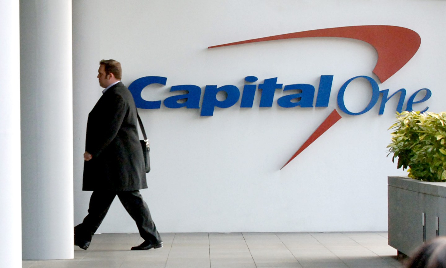 A man walks past a Capital One sign