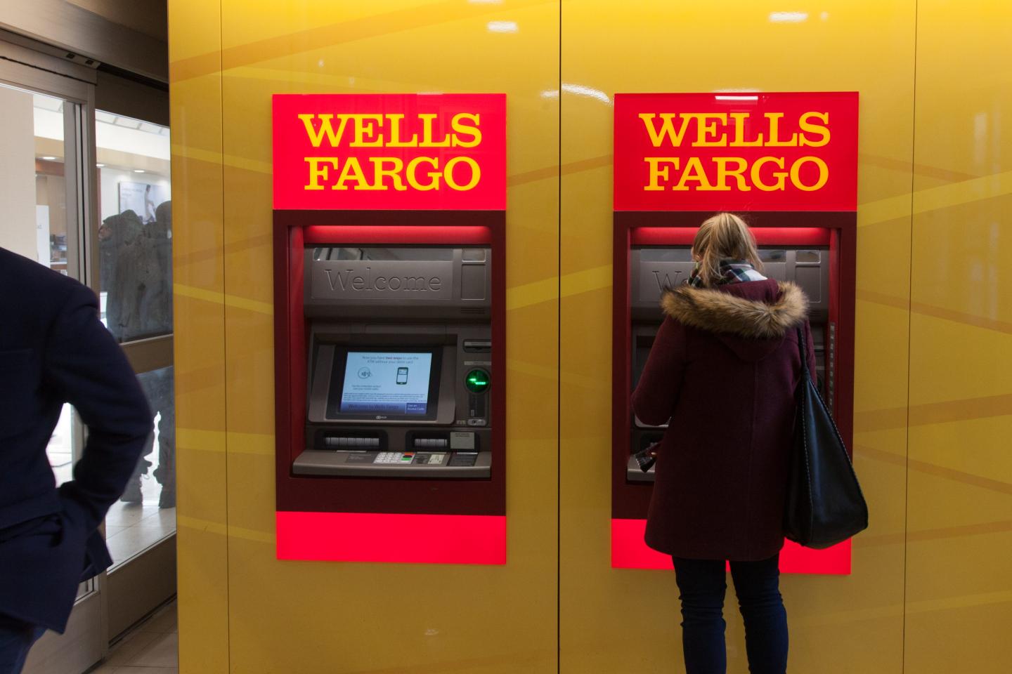 A customer uses an automatic teller machine (ATM) inside a Wells Fargo & Co. bank
