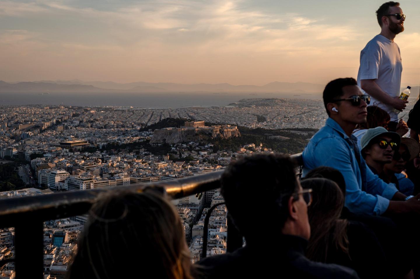 Visitors watch the sunset over the city from Lycabettus Hill in Athens, Greece