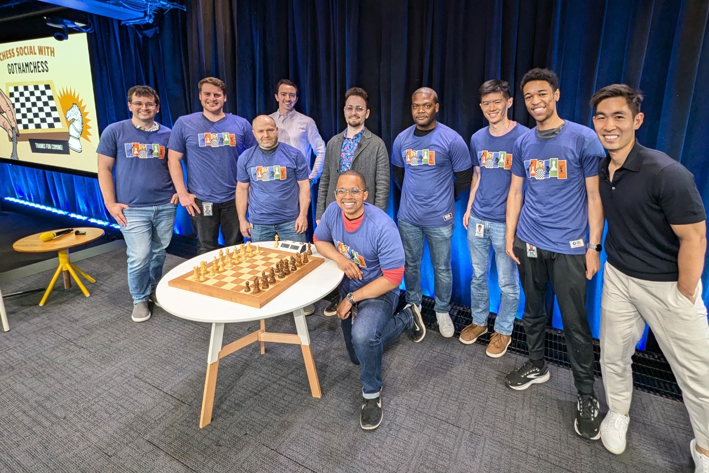 Members of Google's chess community including Kola Adeyemi (background, forth from right), Google's team captain for this weekend's FIDE World Corporate Chess Championship, pose with International Master (IM) and Chess influencer Levy Rozman, known online as GothamChess (background, center in blazer).