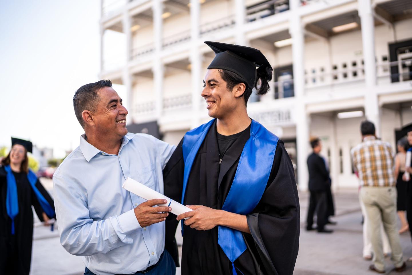 Young graduate man talking with his father on the graduation.