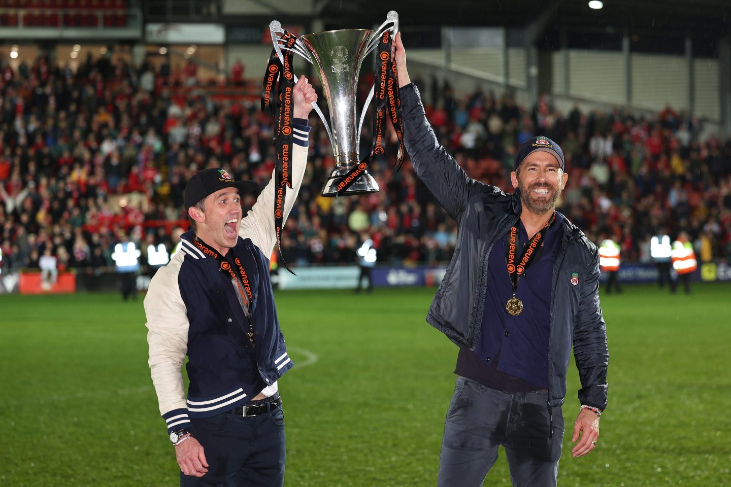 Given the success of Rob McElhenney and Ryan Reynolds—seen here holding the Vanarama National League Trophy on April 22, 2023, as Wrexham AFC celebrate promotion back to the English Football League—has led to skyrocketing interest in sports investments.