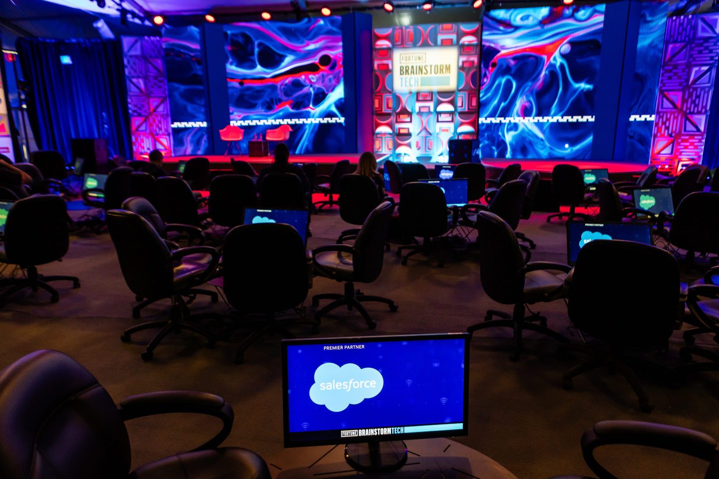 empty chairs surround a brightly lit conference stage