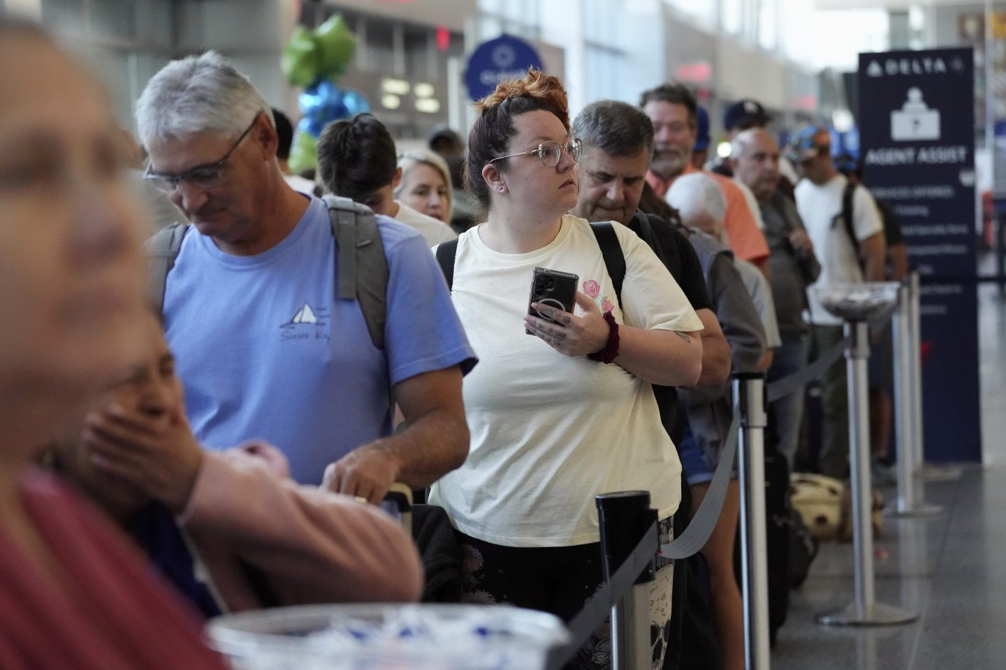 Kaycee Friend, center, of Pendleton, Ore., waits in line at the Delta Terminal after her flight was cancelled, on July 19, 2024, at Logan International Airport in Boston.