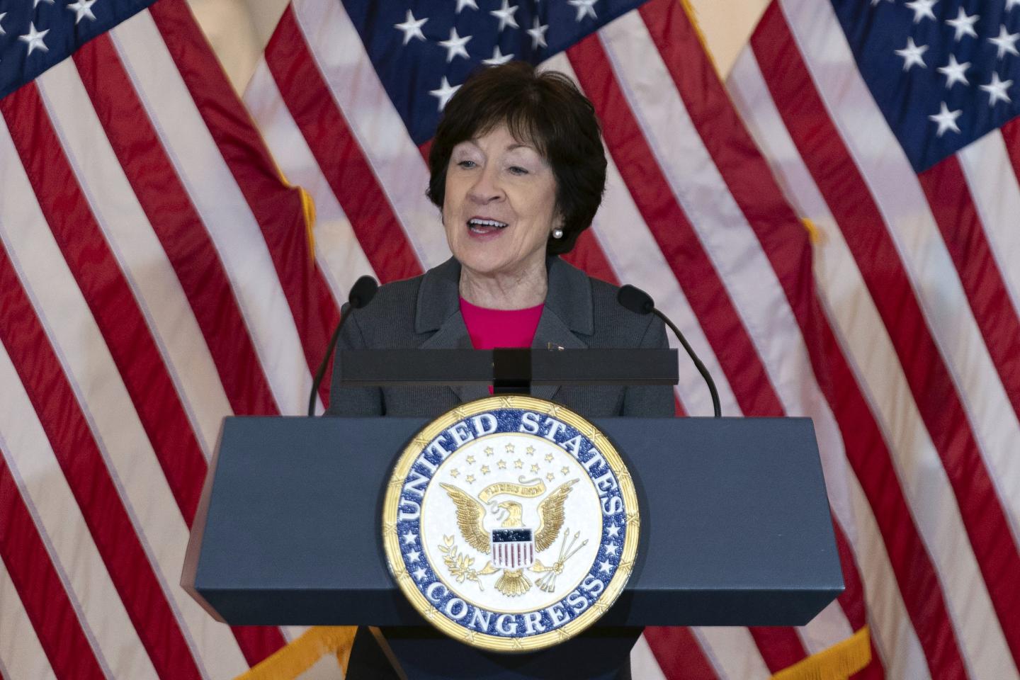 Sen. Susan Collins stands in front of US flags