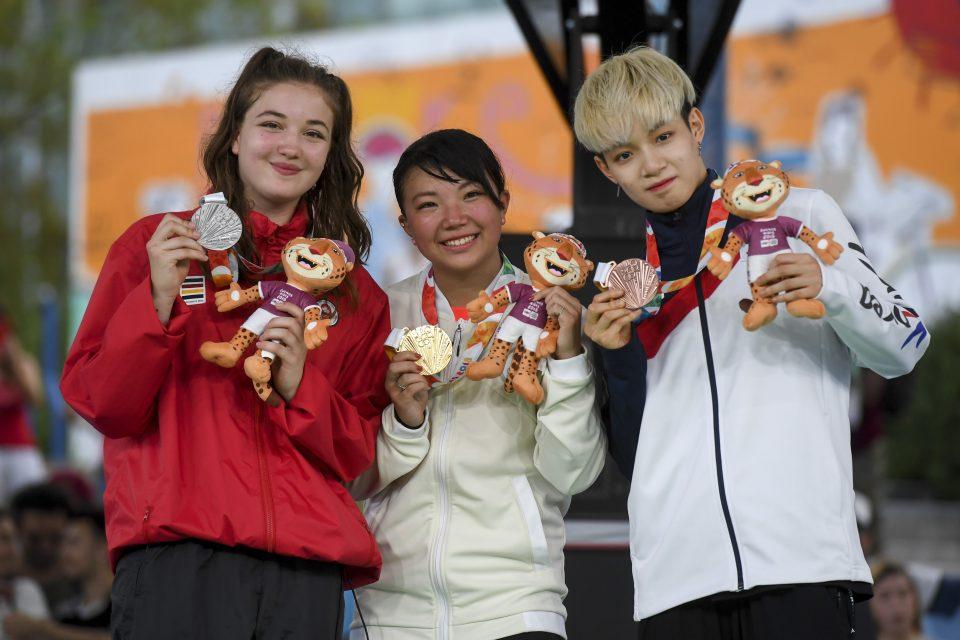 3 people standing together wearing medals