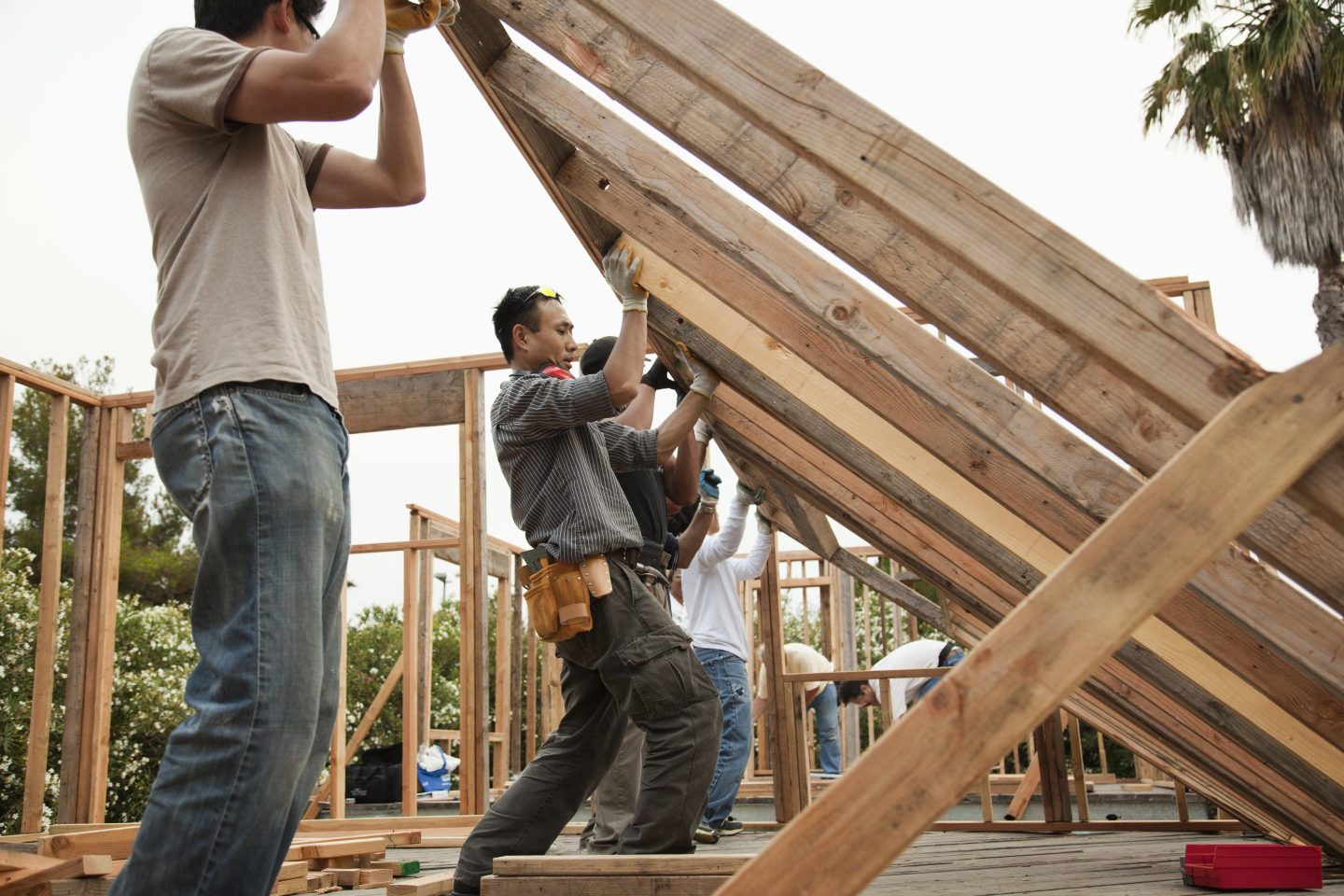 Construction workers lifting house frame