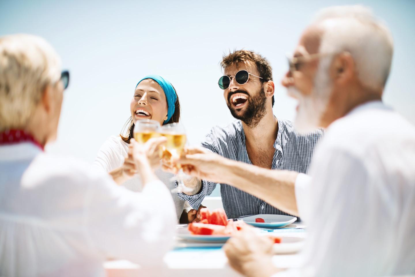 Family toasting with a white wine outdoors on the beach restaurant.
