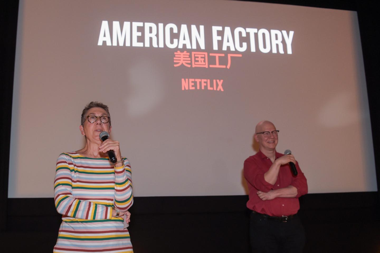 two people stand in front of screen
