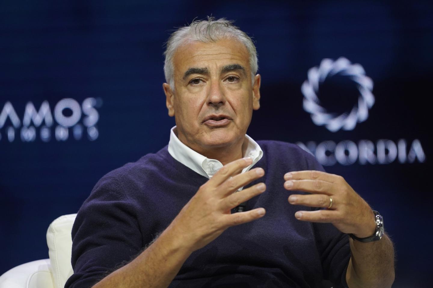 Marc Lasry sits in a chair, seemingly unable to touch his fingers together