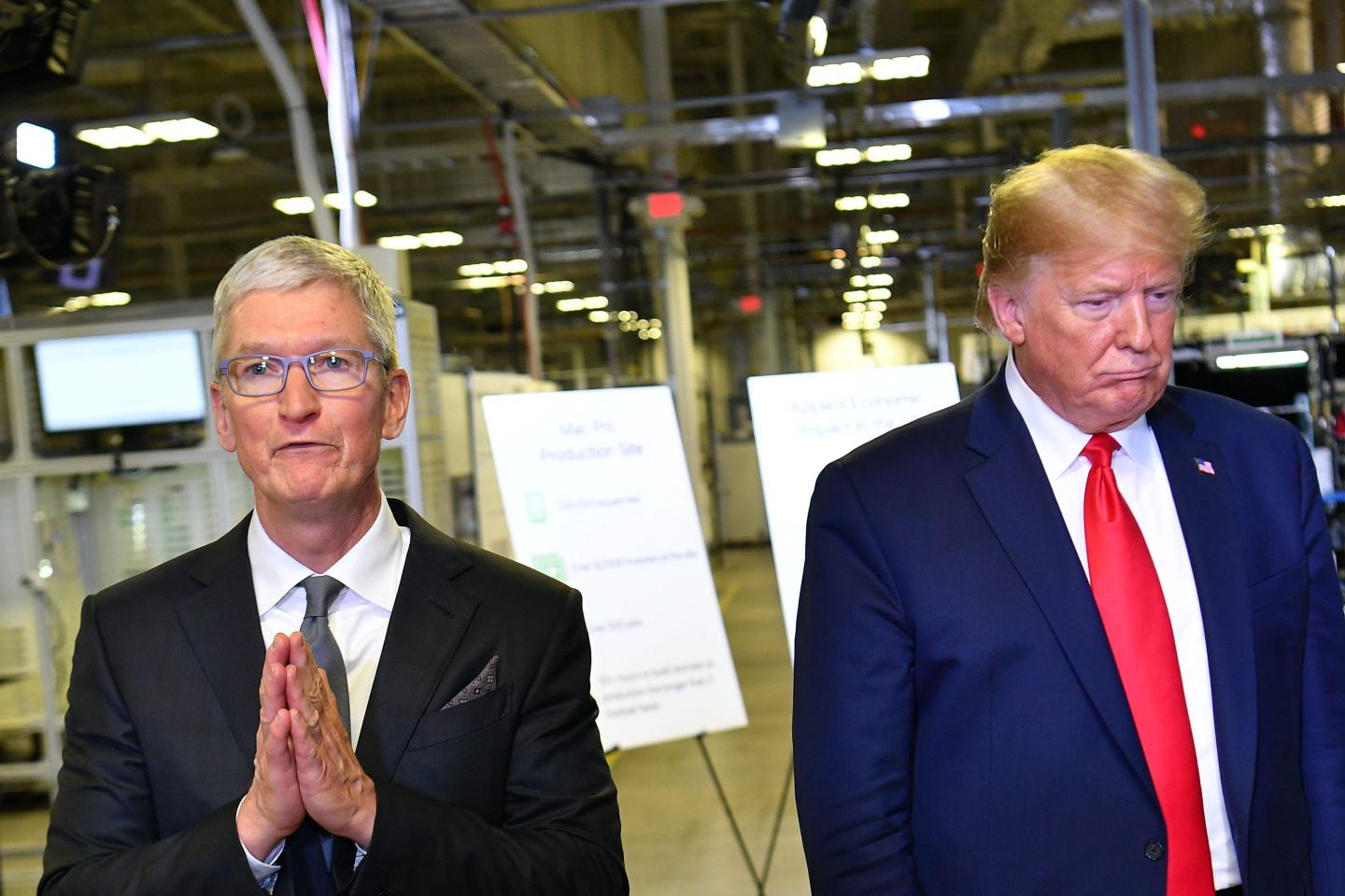 Apple CEO Tim Cook stands next to former President Donald Trump during a visit to a manufacturing plant
