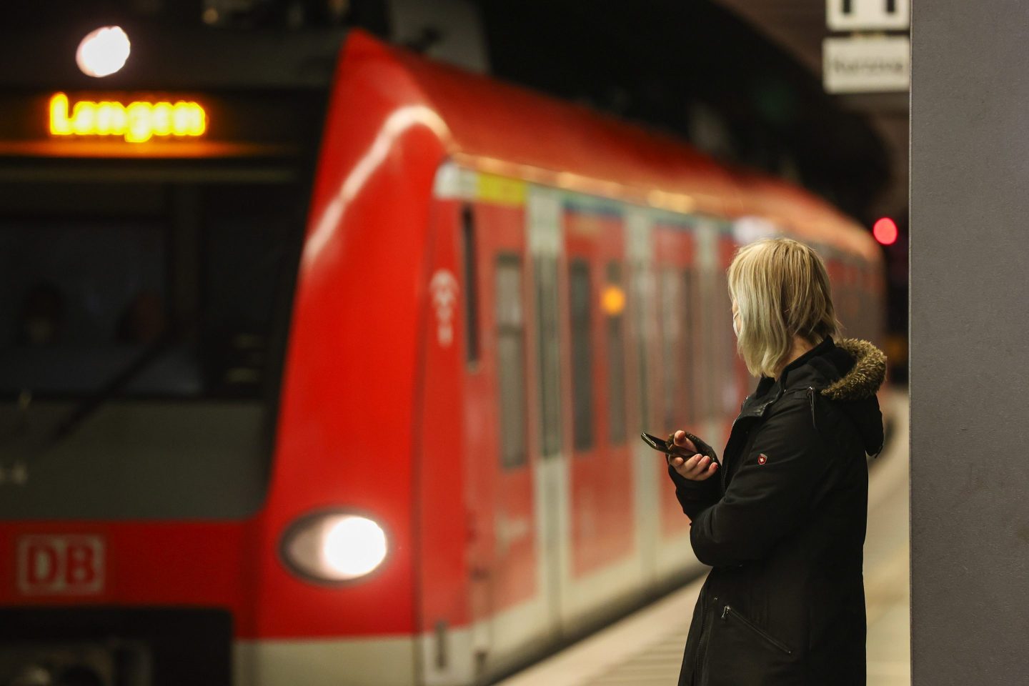 woman watching as a red train arrives