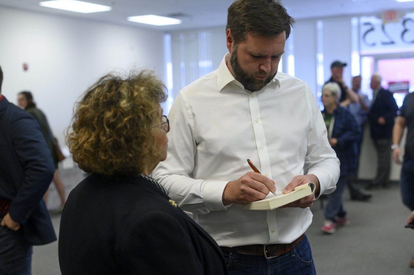 J.D. Vance signs a copy of his book Hillbilly Elegy for a woman during his campaign for Senate.