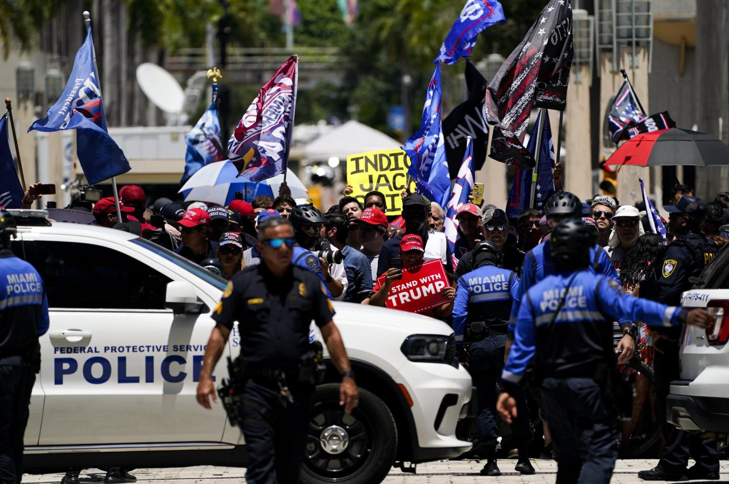 Police officers standing in front of a crowd of pro-Trump supporters.