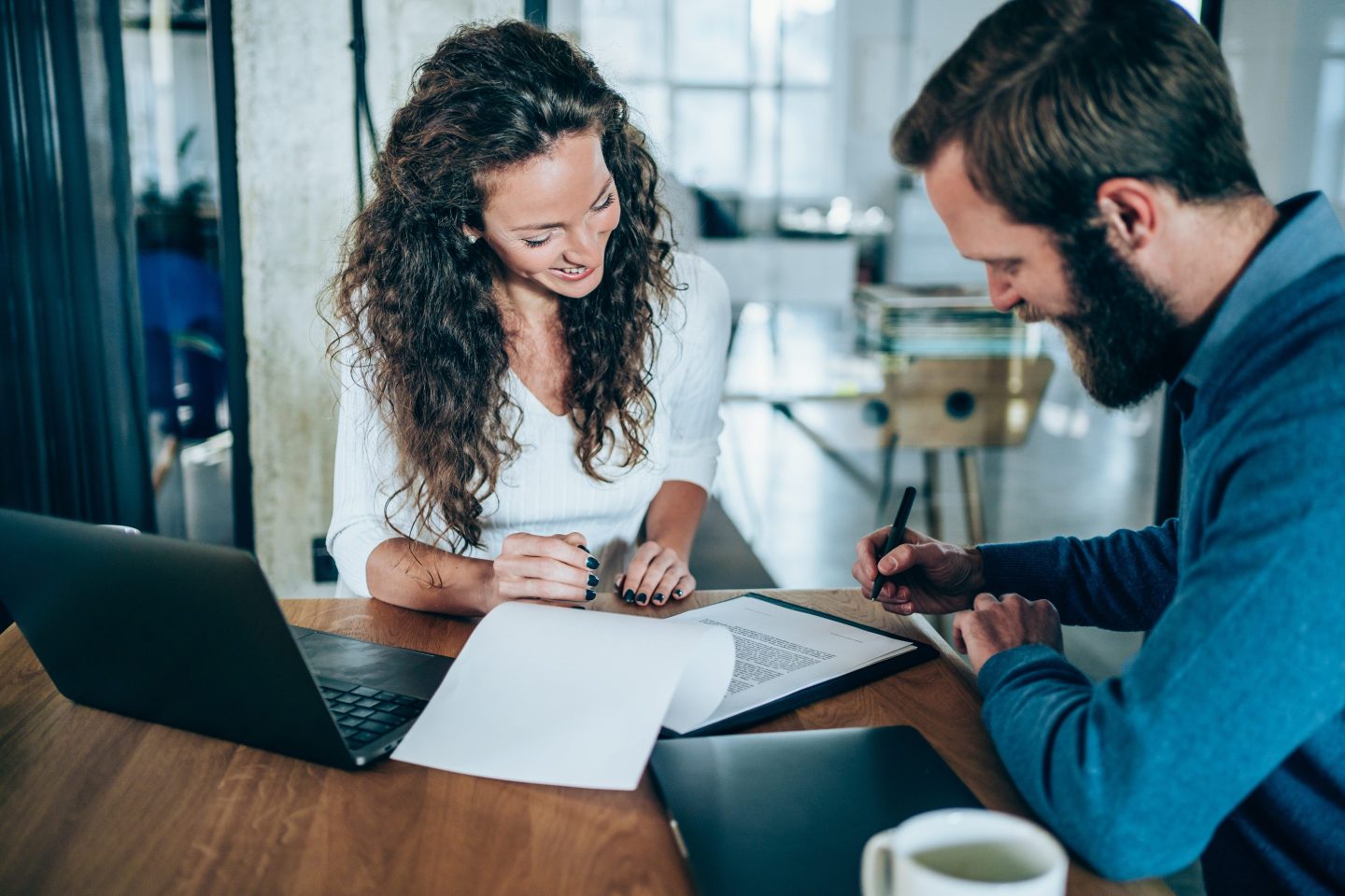 Shot of two business persons filling in paperwork in an office. Businessman and businesswoman signing a document in board room.